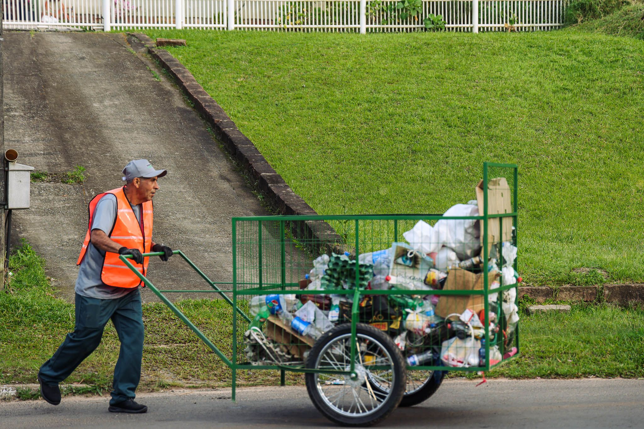 Eloi, 63, a graduate of Projecto Reciclar, pushes a green cart filled with collected recycles.